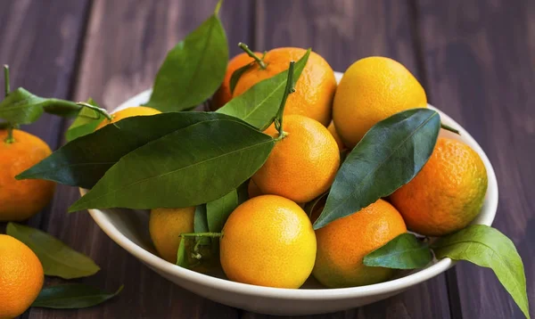 Fresh clementines heap with leaves on wooden background, sweet o — Stock Photo, Image