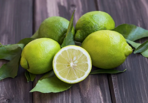 Fresh green lemons , citrus fruits heap with leaves on wooden ba — Stock Photo, Image