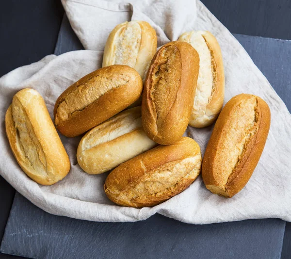 Petits pains fraîchement cuits sur une serviette en lin, tas de petits pains entiers — Photo