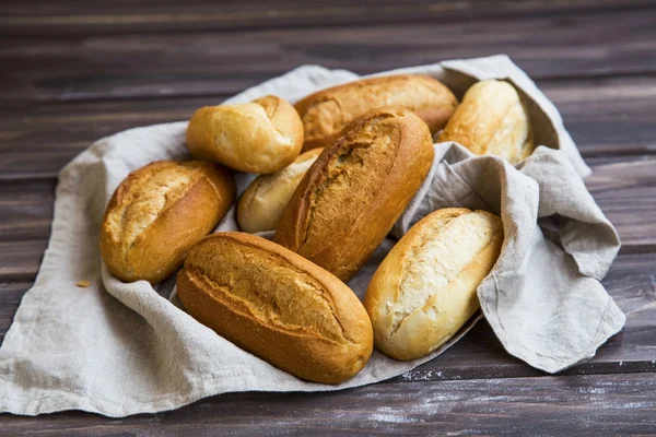 Freshly baked bread buns on a linen towel, whole bread buns heap — Stock Photo, Image