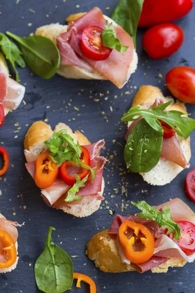 Szendvics falatok vagy crostinivel elrendezése prosciutto sonka, zöld s — Stock Fotó