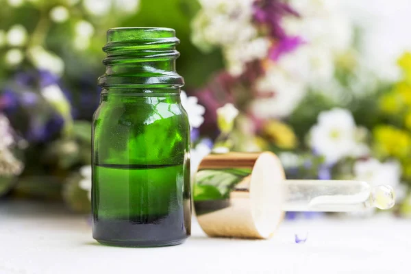 Esenciální olej láhev s léčivými rostlinami v pozadí — Stock fotografie