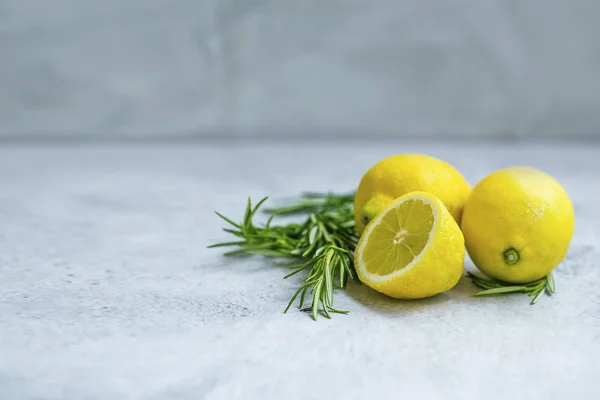 Lemons and rosemary branches on grey concrete background — ストック写真