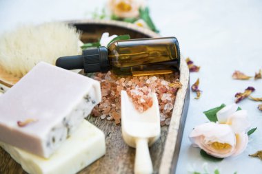 Doğal sabunlar, yağ şişesi, banyo tuzu ve güller, doğal cilt bakımı, temiz güzellik. 