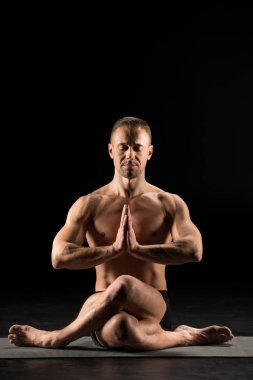 Adam yoga pozisyonunda oturuyor.