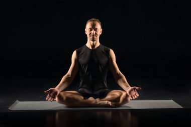 Adam yoga pozisyonunda oturuyor.