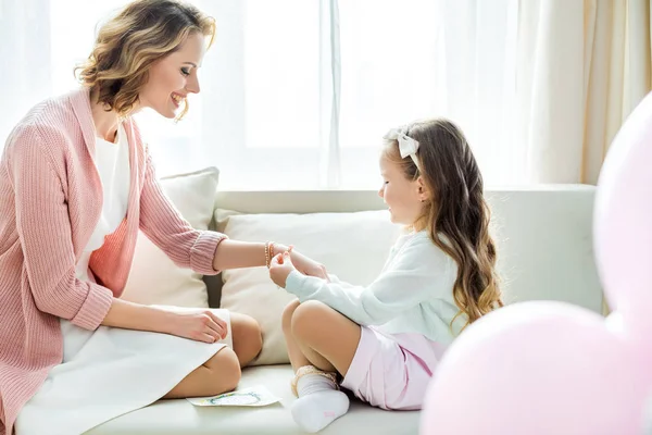 Girl putting jewelry on mother — Stock Photo, Image