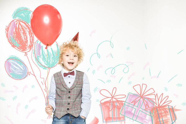 boy in cone hat with balloons