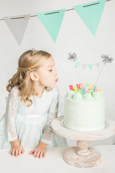 Girl blowing at birthday cake — Stock Photo