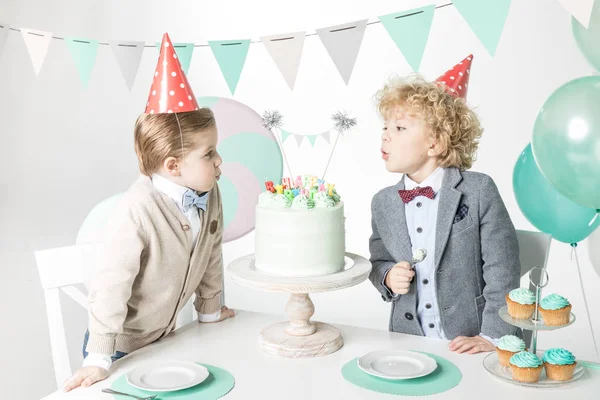 Мальчики задувают свечи на торте — стоковое фото