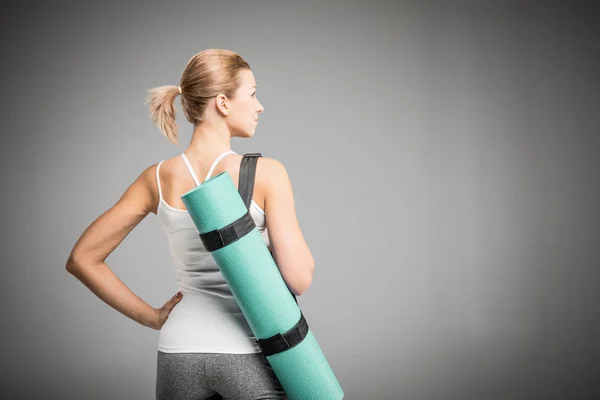 Sportswoman holding yoga mat — Stock Photo