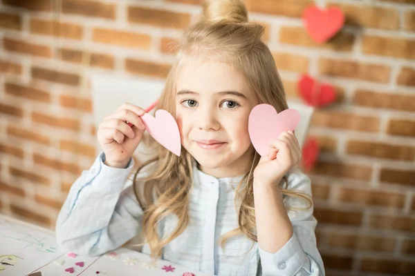 Chica sosteniendo corazones de papel - foto de stock