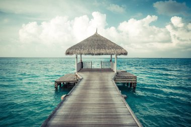 Su bungalovları ve Maldivler 'de uzun iskelesi olan güzel bir sahil. Yaz tatili konsepti.