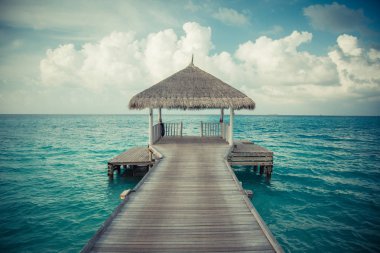 Su bungalovları ve Maldivler 'de uzun iskelesi olan güzel bir sahil. Yaz tatili konsepti.