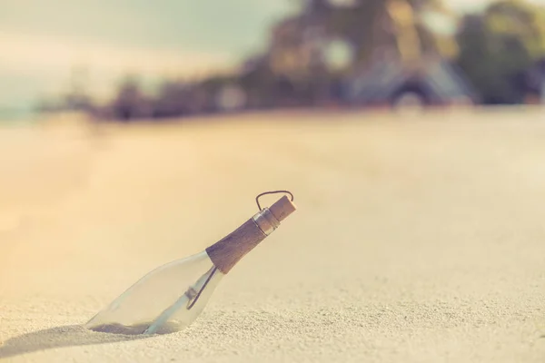 Bottle with a message at sunset in Maldives beach. Relaxing summer holiday background concept.