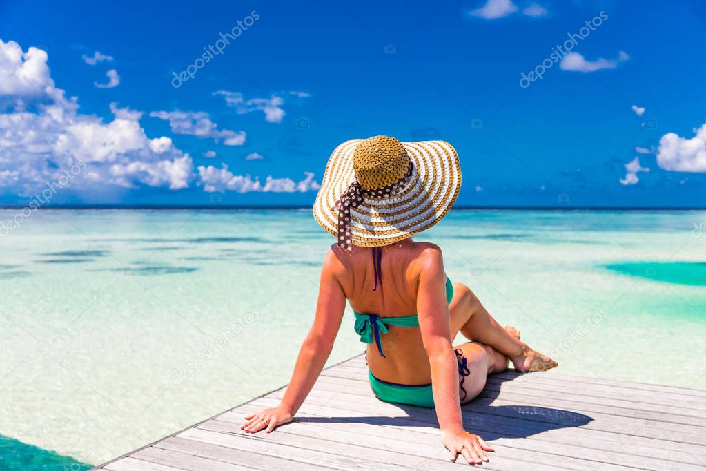 Young slim woman laying on pier, tropical beach, blue water and sky, sunny, tanned skin, bikini, sexy body, sunbathing, tropical vacation, relaxing. Summer travel background