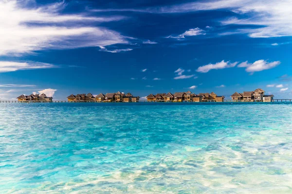 水のバンガローとモルディブの長い桟橋と美しいビーチ。夏の旅行休暇のコンセプト. — ストック写真