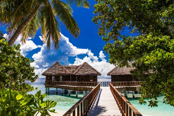 Praia bonita com bungalows de água e longo molhe em Maldivas. Verão viagem férias conceito . — Fotografia de Stock