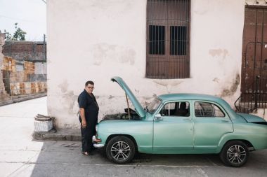 Santiago de Cuba, Cuba - 20 Ocak 2017: adam kırık eski araba yanında durduğunu