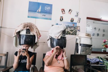 Santiago de Cuba, Cuba - 20 Ocak 2017: Kuaför salon retro saç kurutma makinesi altında oturan kadın