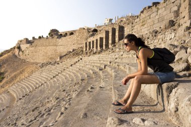 Gün batımında antik amfitiyatro koltuklarda oturan kadın