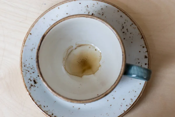 empty blue coffee cup with traces of coffee at the bottom stands on a saucer