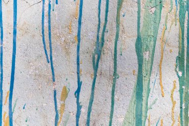 Eski beyaz bir duvarda çok renkli boya izleri var.