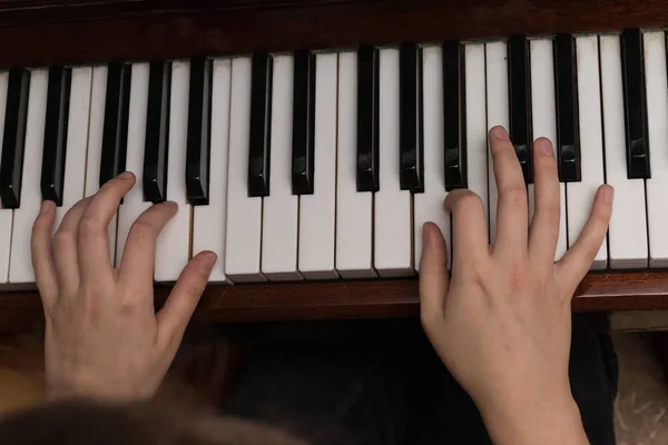 Hands of a girl playing the piano close-up