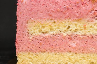 Siyah arkaplanlı yarım bir pasta. Pastayı görünür katmanlar ve pembe dolgularla kes