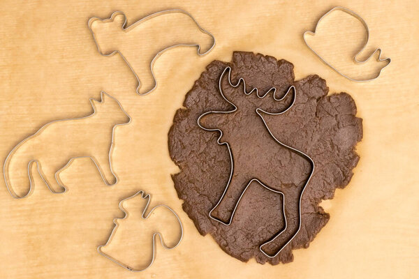A moose-shaped cookie mold lies on a small rolled piece of brown dough