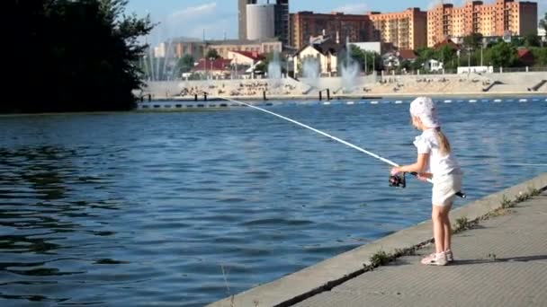 Маленькая девочка активно рыбачит с вращающейся катушкой — стоковое видео