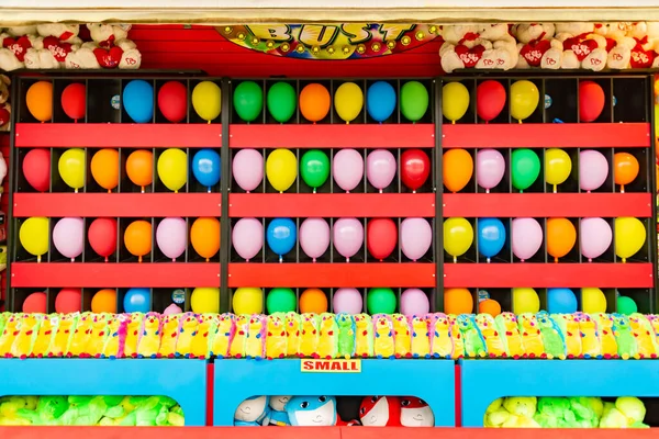 balloons and prizes at a dart throwing game booth at a carnival, fair, or amusement park in America