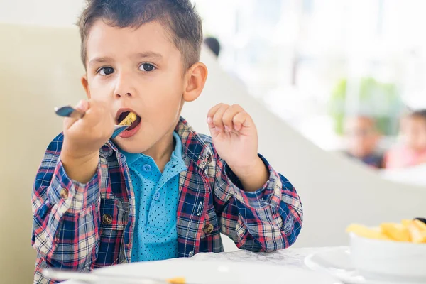 El chico de pelo negro comiendo en un café —  Fotos de Stock