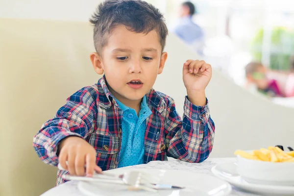 The black-haired boy eating at a cafe — Stock Photo, Image