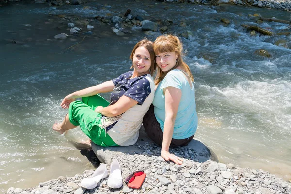 Two young women posing at the mountain river — Stock Photo, Image