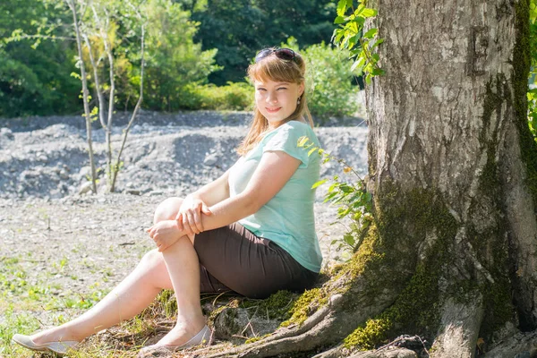 Молодая женщина, сидящая под деревом — стоковое фото
