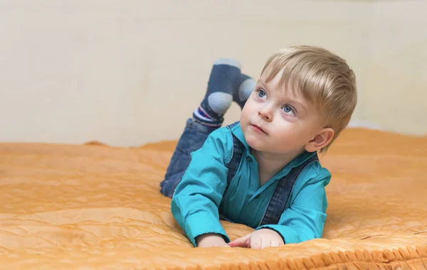 Мальчик в голубой рубашке лежит на кровати — стоковое фото
