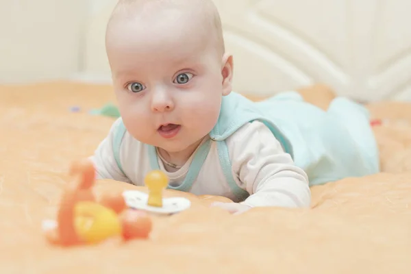 O bebê está em sua barriga e observa os brinquedos — Fotografia de Stock