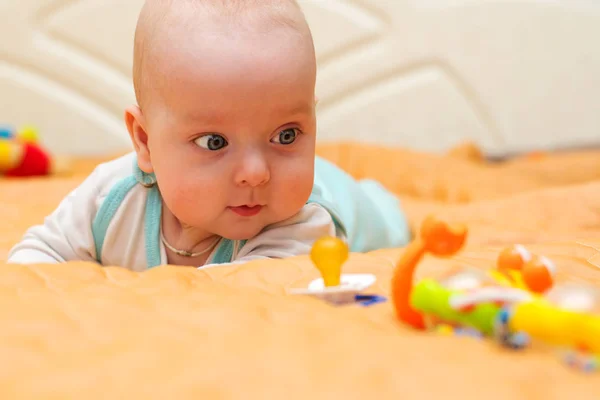 Ребенок лежит на животе и смотрит на игрушки — стоковое фото