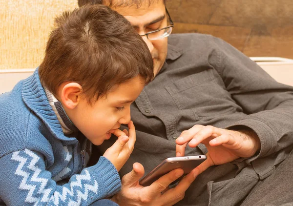 Pappa och son titta på i din smartphone — Stockfoto