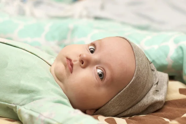 Gloomy baby is lying — Stock Photo, Image