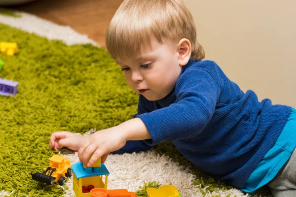 Menino 3 anos de idade jogando deitado no chão — Fotografia de Stock