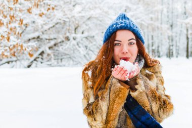Mavi örgü şapkalı çekici genç kadın karda esiyor.