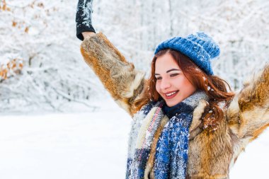 Elleri havada, kışın neşeli genç bir kadın.