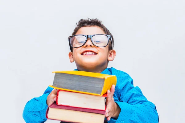 Wesoły chłopiec w okularach z książkami przy biurku — Zdjęcie stockowe