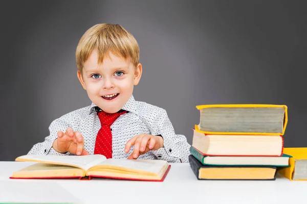 Glad förskolebarn pojke med böcker på en grå bakgrund — Stockfoto