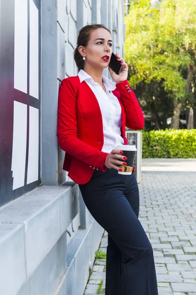 Mujer de negocios sosteniendo café y hablando por teléfono — Foto de Stock