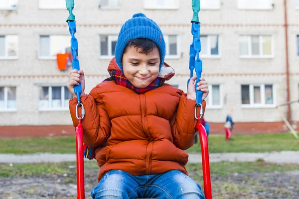 Fröhlicher Junge reitet auf einer Schaukel — Stockfoto