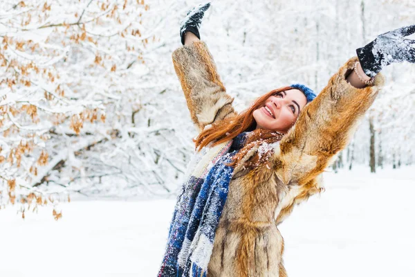 charming young woman with raised hands rejoices in the winter fo