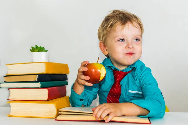 机の上の未就学児がリンゴを食べている。授業中のおやつ. — ストック写真